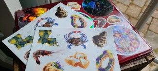 A sticker sheet with 7 different designs- 2 kingcake, a blue crab, an oyster, a shrimp, and beignets.